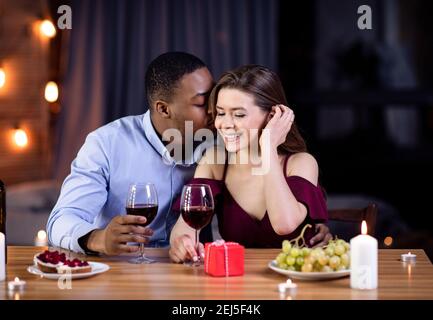 Portrait Of Affectionate Interracial Couple Having Romantic Date In Restaurant Stock Photo