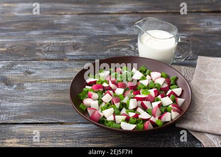 Fresh radish salad with green onionson a wooden background, rustic style. Delicious homemade food Stock Photo