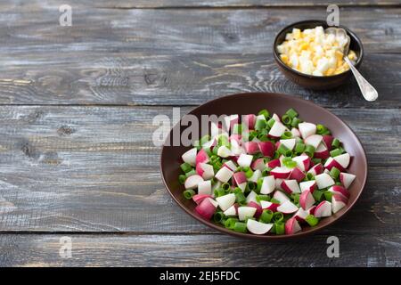 Fresh radish salad with green onions and boiled egg on a wooden background, rustic style. Delicious homemade food Stock Photo