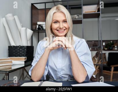 Smiling mid aged woman looking at web cam video calling in virtual chat meeting. Stock Photo