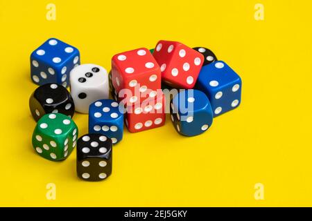Many dice of various colors are on the yellow background. The dice are piled up on a yellow scene. Stock Photo
