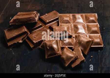 Tablet pieces of dark chocolate on a dark and industrial surface. Stock Photo