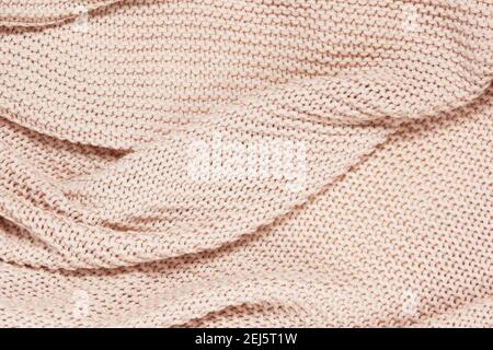 Textured surface of knitted cotton wave plaid, top view, closeup. Soft dusty pink pastel wool backdrop. Seasonal cosiness flat lay. Scandinavian minim Stock Photo