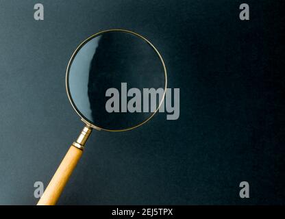 Close up single Magnifying Glass with cream wood Handle on blue paper. Stock Photo
