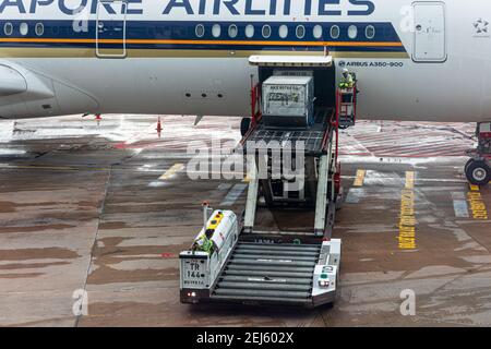 A ULD loader lifting a unit load device (ULD) from apron dollies to an aircrafts cargo bay of a Singapore Airlines machine at Changi Airport Singapore