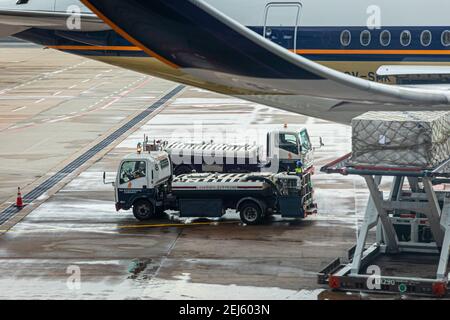 Lavatory service vehicles for emptying and refilling lavatories onboard aircraft of a Singapore Airlines machine at apron of Changi Intern. Airport Stock Photo