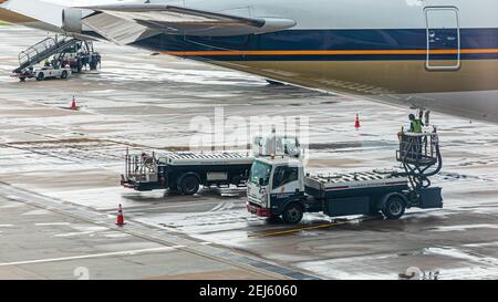 Lavatory service vehicles for emptying and refilling lavatories onboard aircraft of a Singapore Airlines machine at apron of Changi Intern. Airport Stock Photo