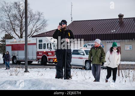 Cleveland, Ohio, USA. 21st Feb, 2021. Cleveland resident Andrew Sowinski takes video of people being rescued off the ice of Lake Erie by members of the USCG Ice Rescue Team from Station Cleveland, as well as other local rescue agencies, late Sunday afternoon, February 21, 2021 at Edgewater Park in Cleveland, Ohio. At 12:43 EST, the National Weather Service in Cleveland issue a warning to not go onto the ice due to development of significant cracks from southerly winds. According to a Tweet from the USCG Great Lake, the '''¦ USCG ice rescue team rescued 6 individuals via the ice skiff and Stock Photo