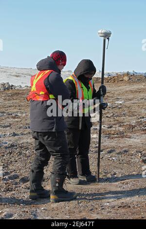 Two surveyors working on the Inuvik-Tuktoyaktuk Highway during winter construction, Northwest Territories, Canada's Arctic. Stock Photo