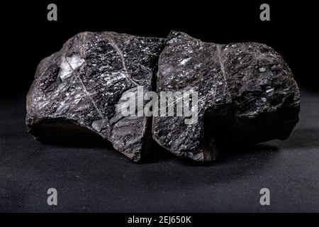 A lump of brown coal laid on a table. Mineral used to generate energy. Dark background. Stock Photo