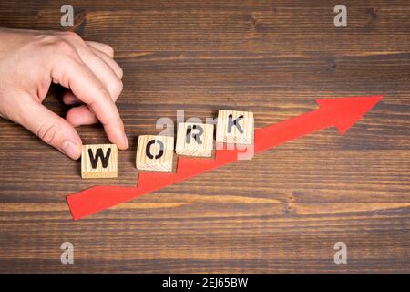 WORK. Career, bonuses and benefits concept. Red arrow indicates the development and growth. Steps, wooden background. Stock Photo