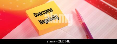 Overcome Negativity. The text is written on a yellow sticky note that lies on the table. Selective focus, toning. Stock Photo