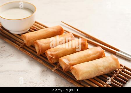 Tasty fried spring rolls and sauce on light background Stock Photo