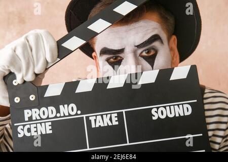 Male pantomimist with movie clapper on color background Stock Photo