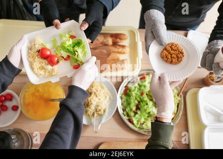 Volunteers giving food to homeless people in warming center Stock Photo
