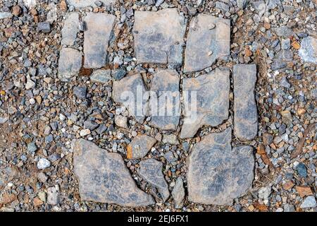 A dirty broken stone tile on gravel. The tile is arranged to it is obvious how it fit together before it was broken. Some bits missing. Stock Photo