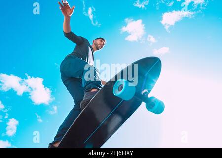 Skateboarder in action. Man riding on a skateboard outdoors on sunny summer day. Blue sky background. Stock Photo
