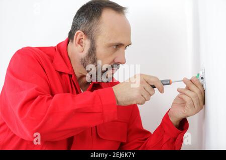 electrician using screwdriver on plug socket Stock Photo