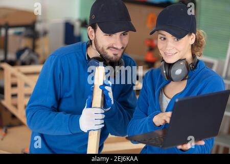 young colleagues with laptop in the carpenter workroom Stock Photo