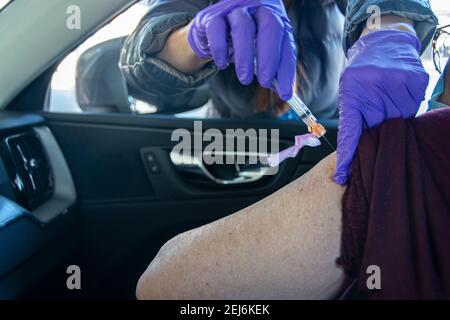 An 84 year old, Latina woman, gets her second Moderna vaccine injection  to help stop the spread of the COVID-19 virus; Dodger Stadium, L.A. CA USA. Stock Photo