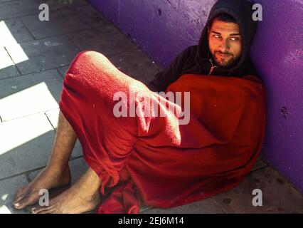 Homeless young man lounged on a pavement, London, England, UK. Stock Photo