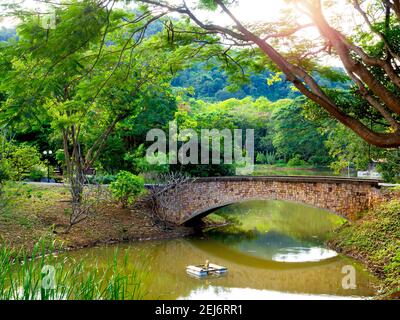 Stone bridge crosses a stream near the mountain. Old vintage brick bridge over the river in the park with beautiful green landscape.