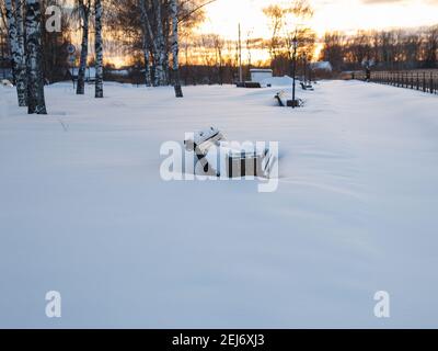 Snow-covered benches in park on winter evening. Stock Photo