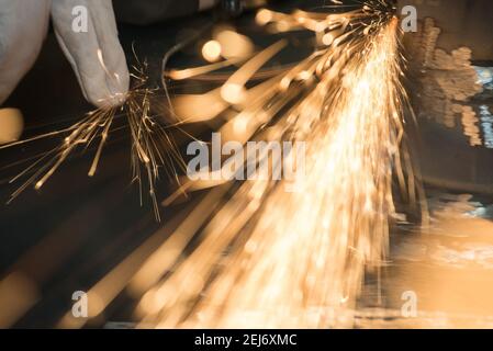 Beautiful yellow sparks from the rotation and cutting of metal by hand grinder as background Stock Photo