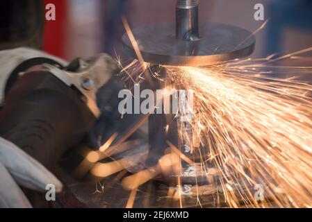 Beautiful yellow sparks from the rotation and cutting of metal by hand grinder as background Stock Photo