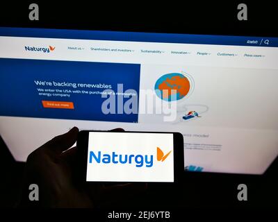 Person holding smartphone with logo of Spanish energy company Naturgy Energy Group S.A. on screen in front of website. Focus on phone display. Stock Photo