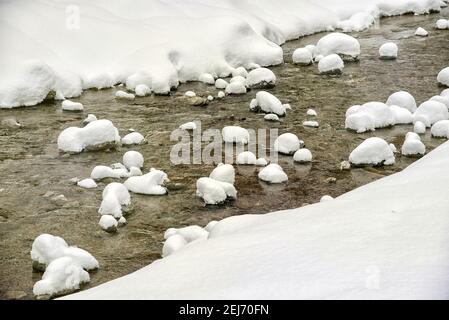Frozen mountain river with ice flowing near snowy coasts on cold winter day in countryside Stock Photo