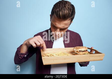 Man in shirt hamburgers french fries eating blue background Stock Photo