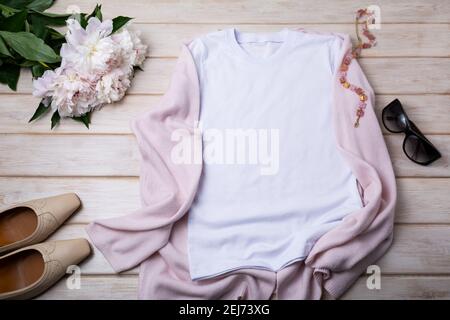 White women’s cotton T-shirt mockup with sunglasses, necklace, pink knit jacket, flat shoes and peony bouquet. Design t shirt template, tee print pres Stock Photo