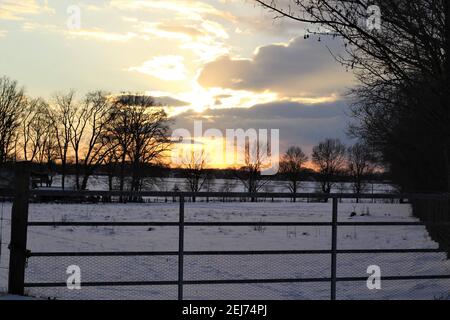 A beautyful sunset with cloudy sky a cattle gate in the foreground Stock Photo