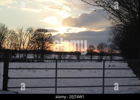 A beautyful sunset with cloudy sky a cattle gate in the foreground Stock Photo