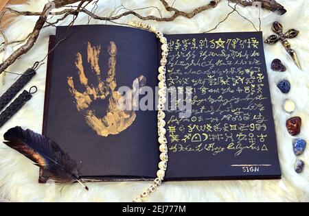 Sell soul to devil concept, black magic book with palmprint and quill.  Esoteric, gothic and occult background, Halloween mystic concept. No foreign l Stock Photo
