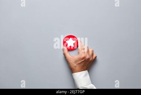 Businessman hand holding a red badge with a star icon. Customer rating or service feedback concept. Stock Photo