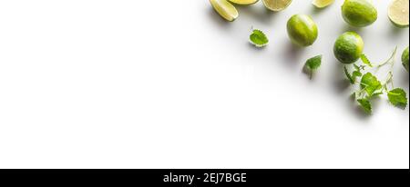 Sliced and whole limes with mint leaves on an isolated white banner background. Stock Photo