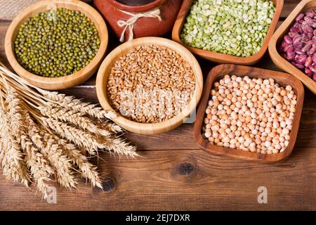 various cereals, seeds, beans and grains on wooden table, top view Stock Photo