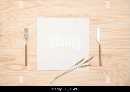 mockup Blank card and cutlery on wooden table. Top view white recipe paper page with mockup text space, invitation card and cutlery on wooden backgrou Stock Photo