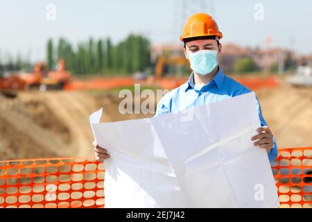 Masked architect in a construction site, covid coronavirus construction concept Stock Photo