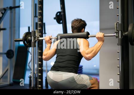 Bodybuilder doing squats using a squat cage in a gym to train his legs Stock Photo