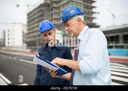 Two architect developers reviewing building plans at construction site Stock Photo