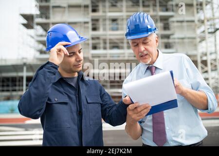 Two architect developers reviewing building plans at construction site Stock Photo