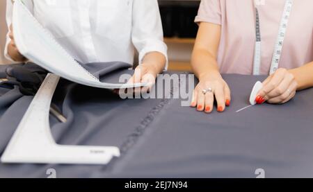 Sew working, two woman dressmaker making pattern on grey material. Stock Photo