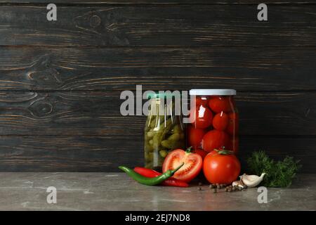 Jars with pickled tomatoes and cucumbers on wooden background Stock Photo