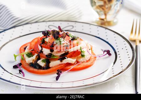 Caprese salad. Mozzarella cheese, tomatoes and basil pesto on plate.  Eco friendly concept. Stock Photo
