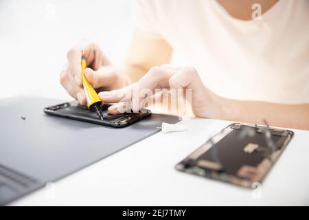 Master disassembles modern mobile phone, repairs and replaces battery, broken screen. Stock Photo