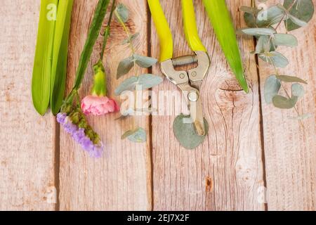 The florist desktop with working tools on light wooden background with place for text. Stock Photo