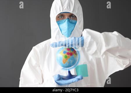 Doctor in protective suit and glasses holding globe Stock Photo